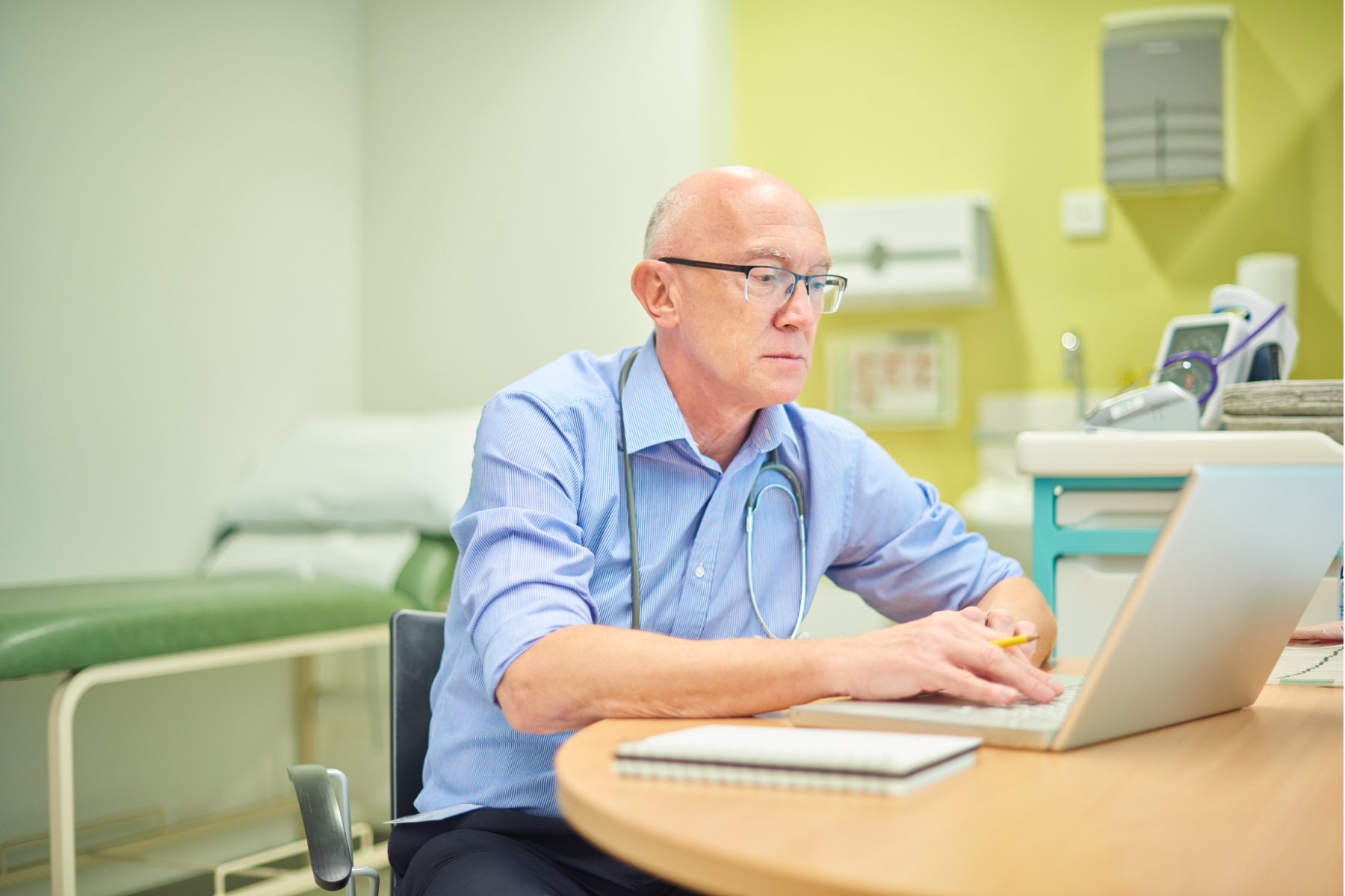 Image of a doctor using a laptop in his exam room