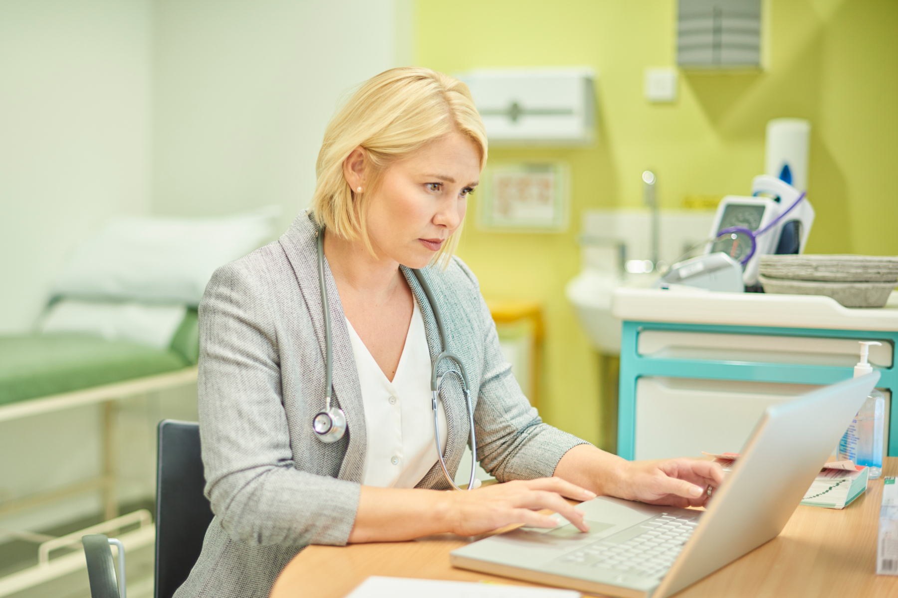 Image of a doctor using her laptop in an exam room