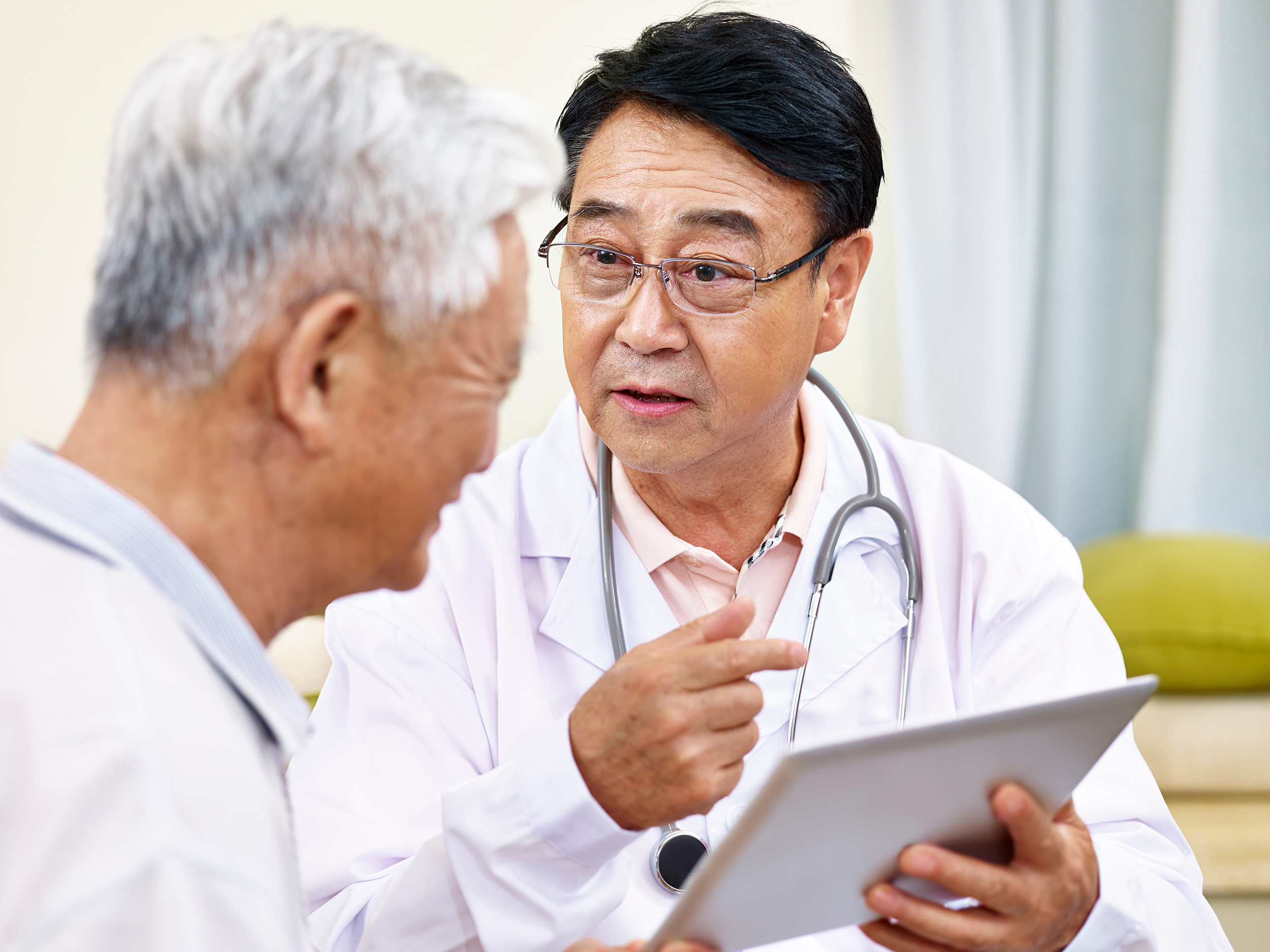 Photo of two doctors talking and looking at a tablet